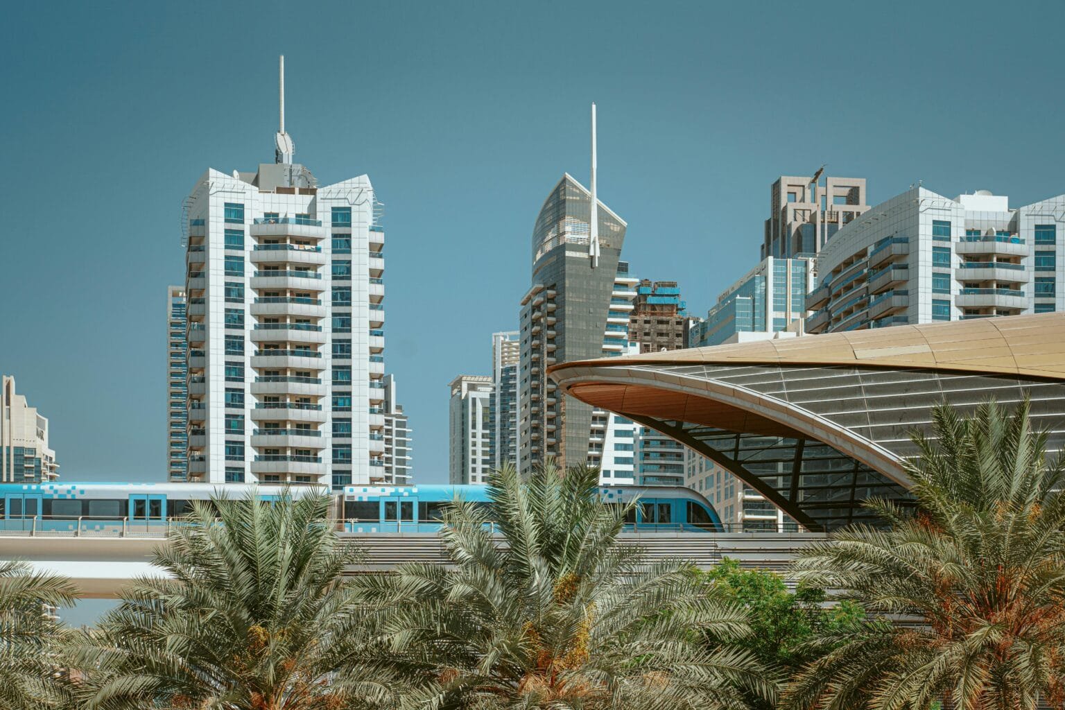 How to buy property in Dubai from India: Dubai Marina skyline with metro and palm trees